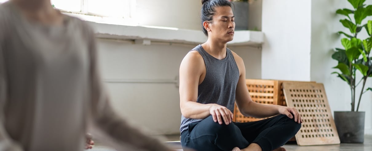 Man sitting down cross legged with eyes closed