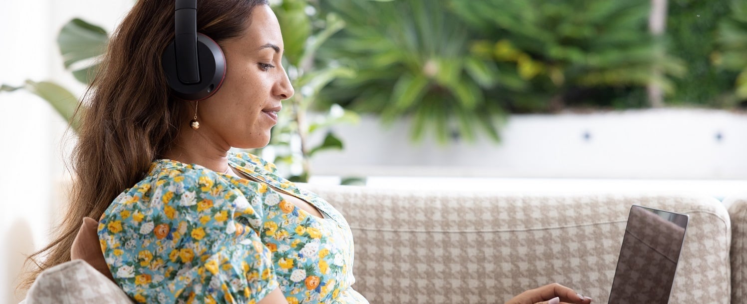 Woman wearing headphones typing on a laptop